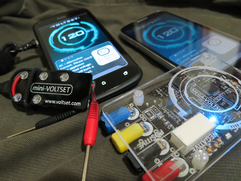 The original Voltset hardware and Android app: two phones showing the cyan ring dial, next to the mini-VOLTSET and MEGA-VOLTSET meter boards.